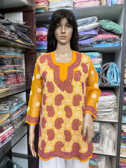 Mannequin wearing a lucknowi chikankari yellow and orange patterned top in a fabric store.