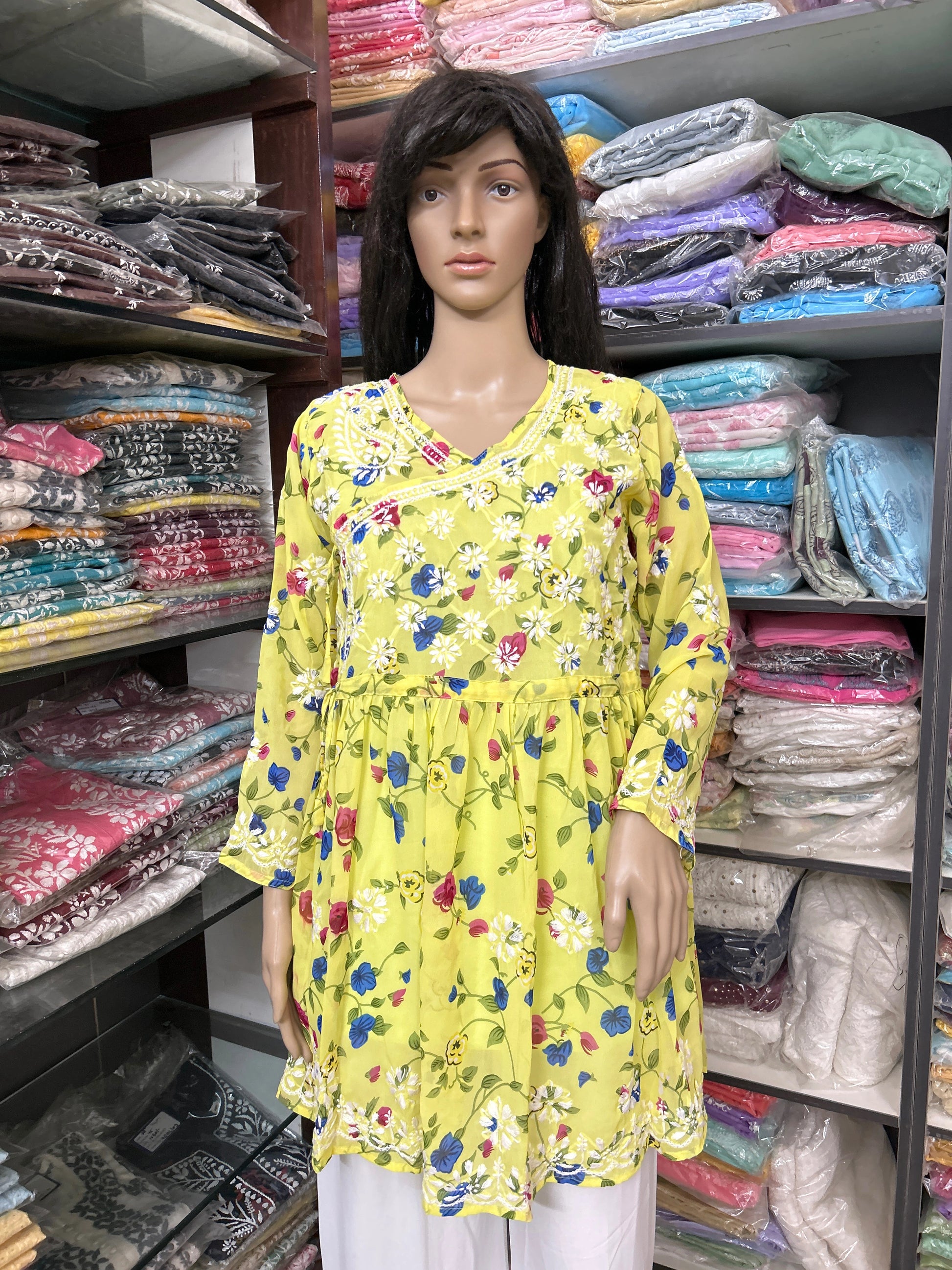 Mannequin wearing a lucknowi chikankari yellow floral dress in a fabric store