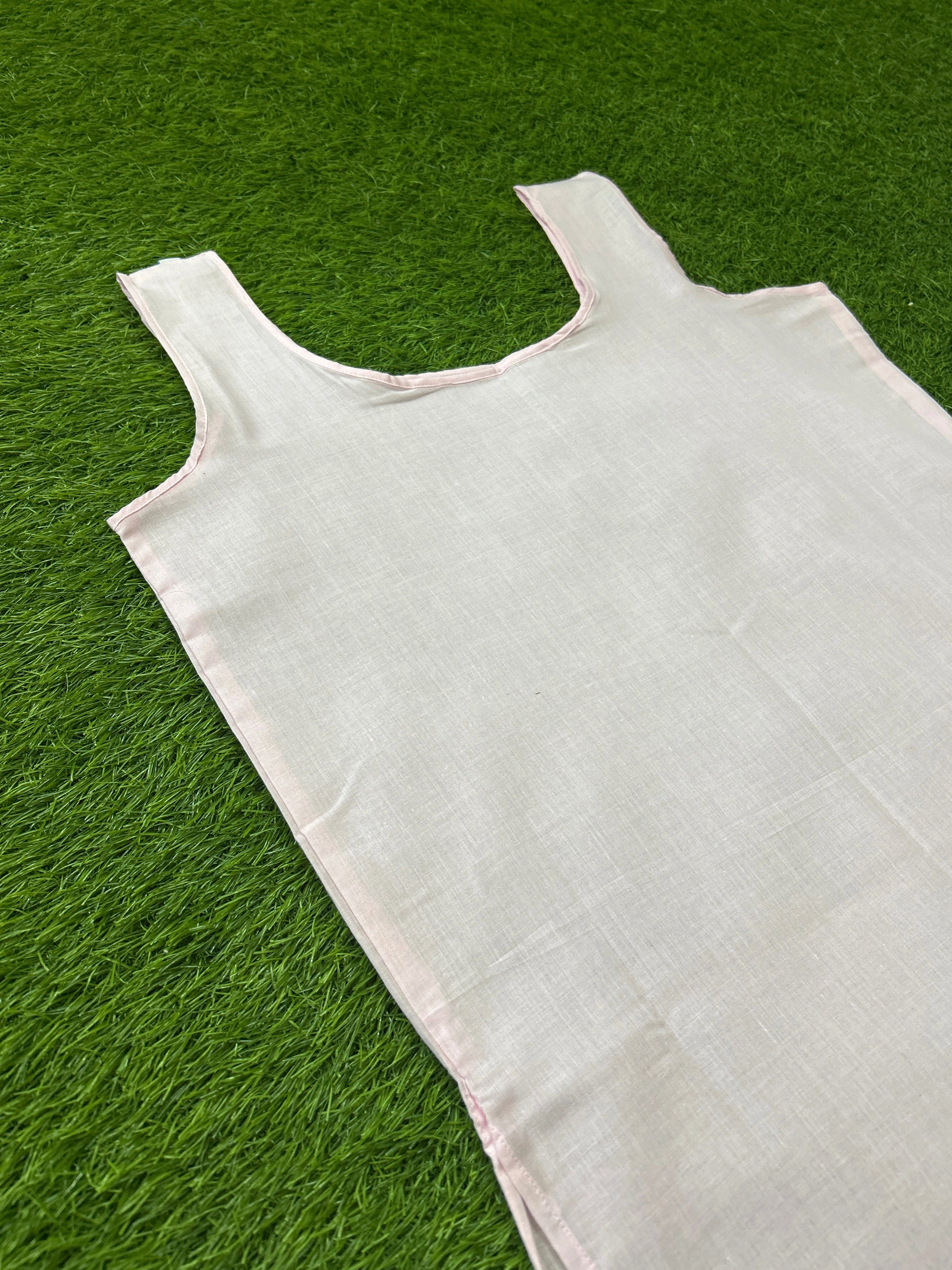 Slip with a wide scoop neckline, laid flat on a vibrant green grass background.