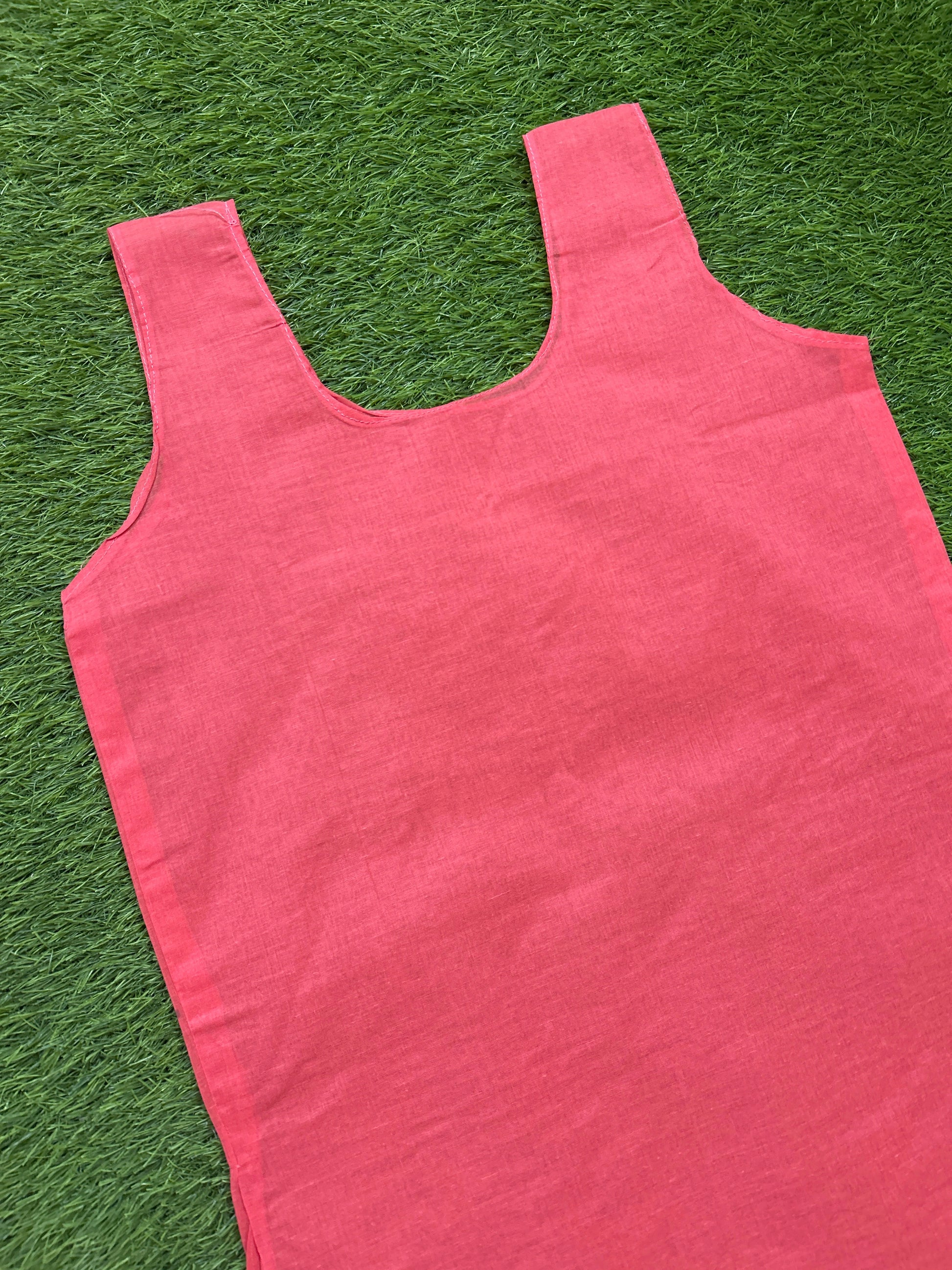 A slip coral pink tank top laid flat on green grass.