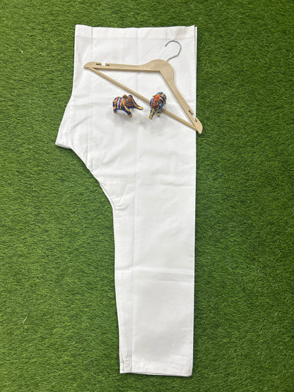 A single white garment laid flat on a green artificial grass background, with a wooden hanger and two small colorful elephant figurines placed on top.
